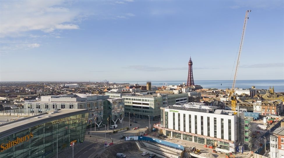 An aerial picture showing a series of modern buildings in the foreground, with The Blackpool Tower, sea and sky in the background.