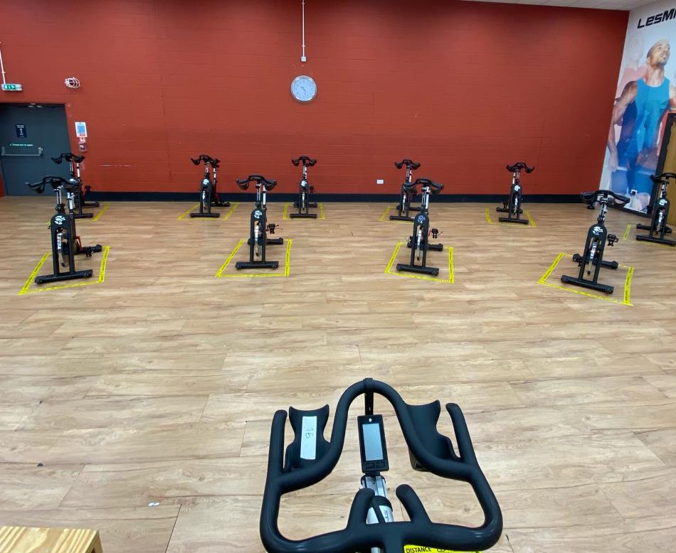 Exercise studio with spin bikes in two rows with floor tape around the bikes