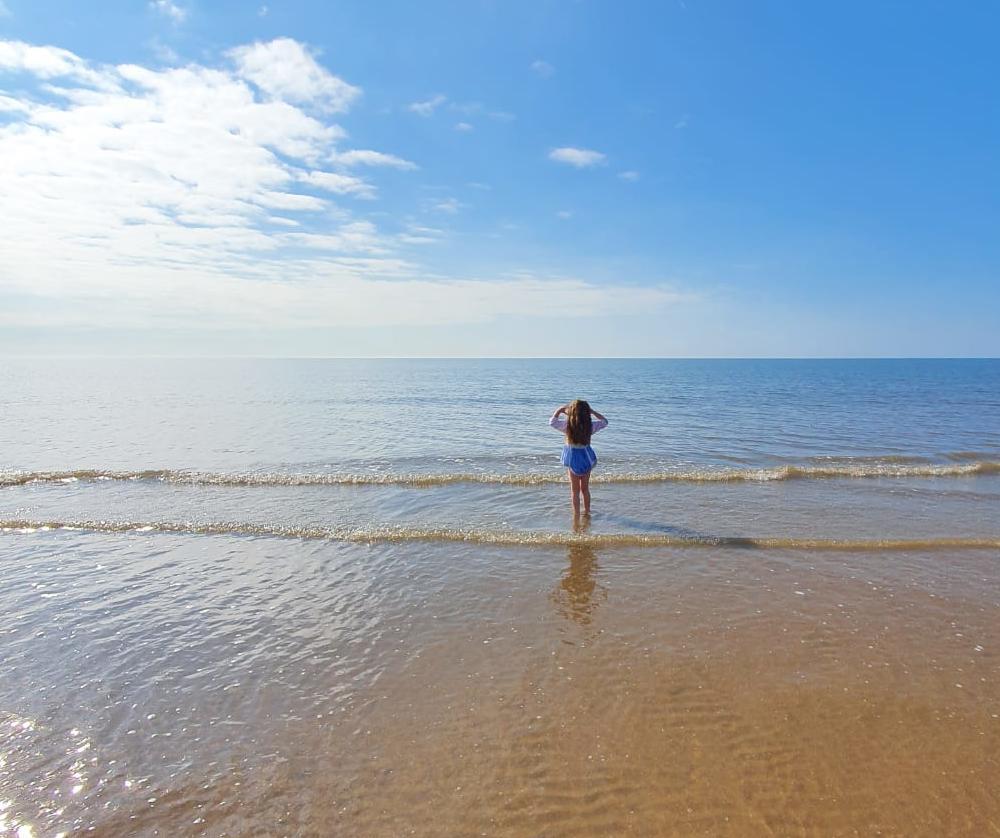 Girl looking out to sea whilst paddling in the water