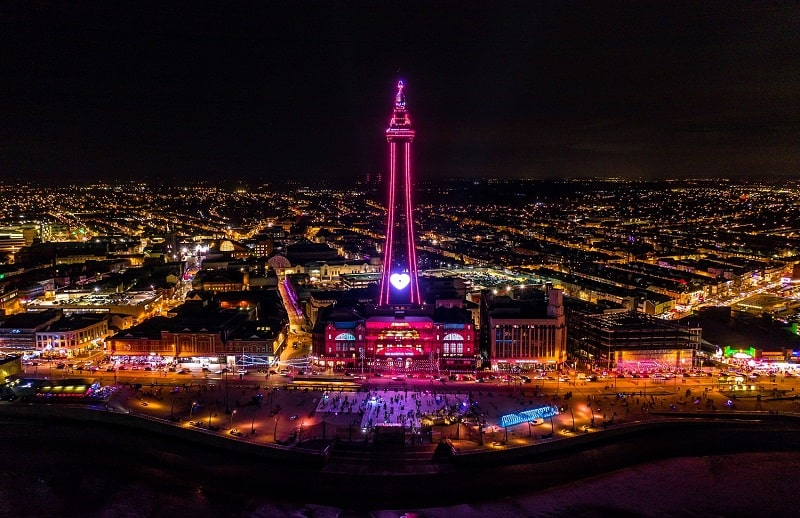 Aerial view of Blackpool Tower and town illuminated at night.