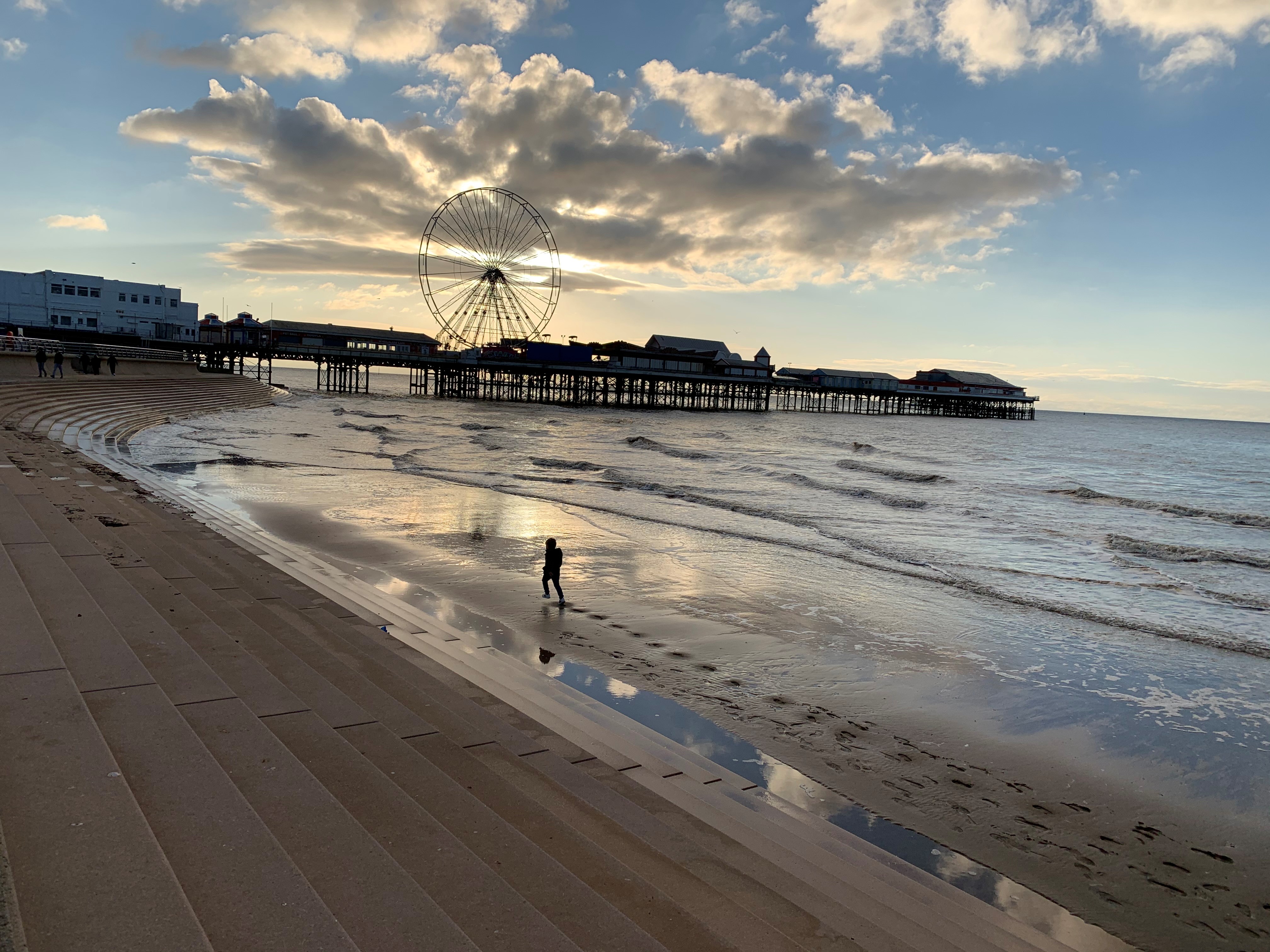 Steps leading down to beach with pier in the distance