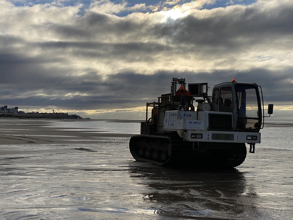 Tracked vehicle in water on beach.