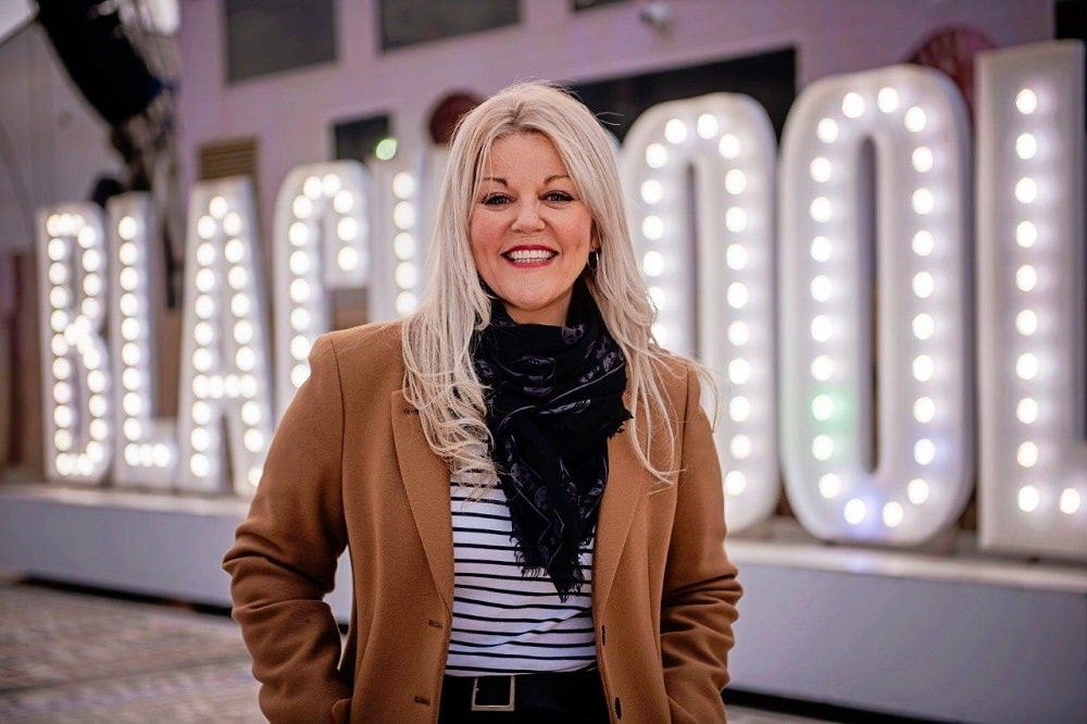 Smiling woman stood in front of an illuminated Blackpool sign