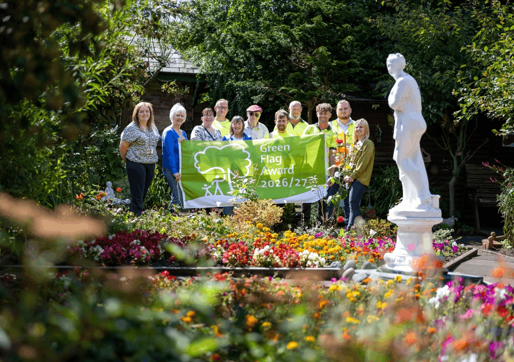 Group of people stood in a garden holding a green flag.