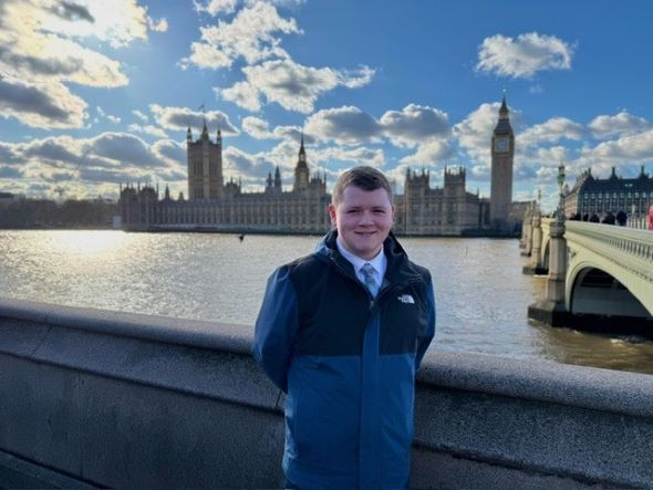 Luke Marwood, 18, in a blue jacket and jeans, stands in front of Big Ben, representing Blackpool at the UK Youth Parliament.