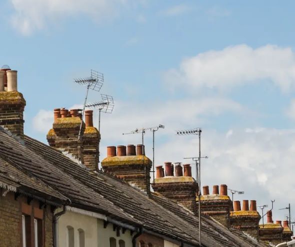 A row of houses featuring multiple chimneys atop their roofs,
