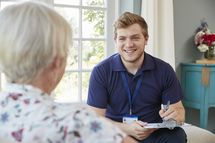 A social care worker chats and makes notes with an older lady