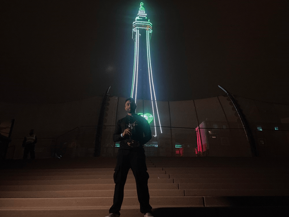 Man standing in front of illuminated tower holder trophy.