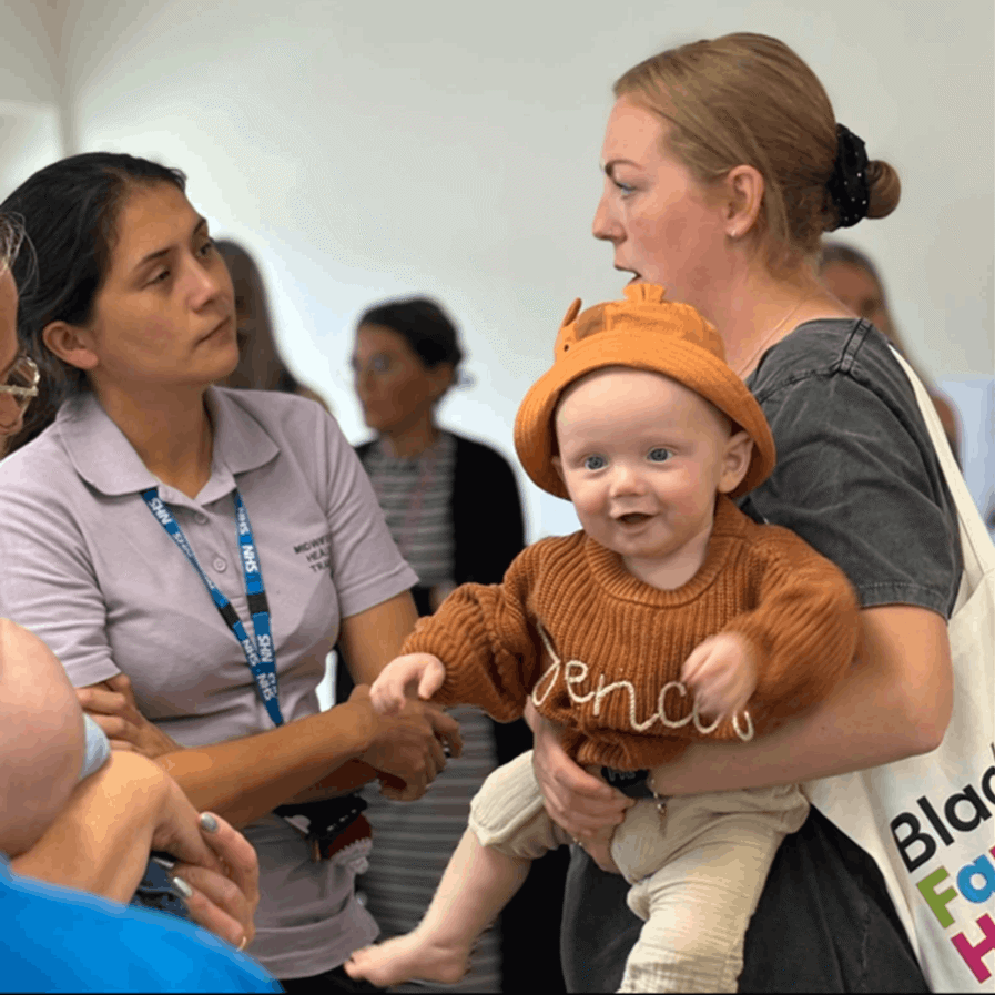 Mum holding baby, talking to a nurse