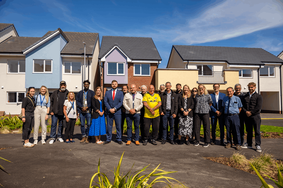 A group of people standing next to a row of houses 