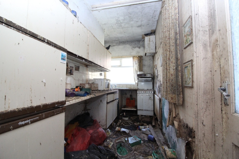 Image shows a kitchen in a poor state of repair, with pigeon droppings across the surfaces