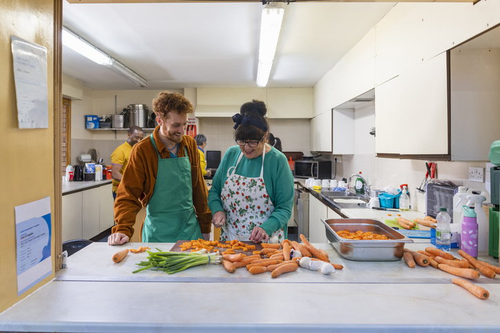 A man and a woman prepare fresh vegetables together in a community kitchen