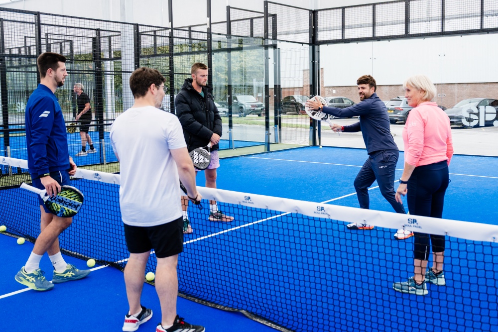 A coach shows players how to play padel