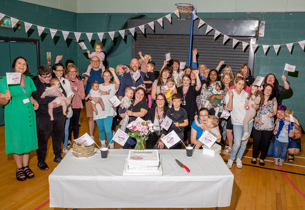 Group of adults with babies and children smiling and cheering