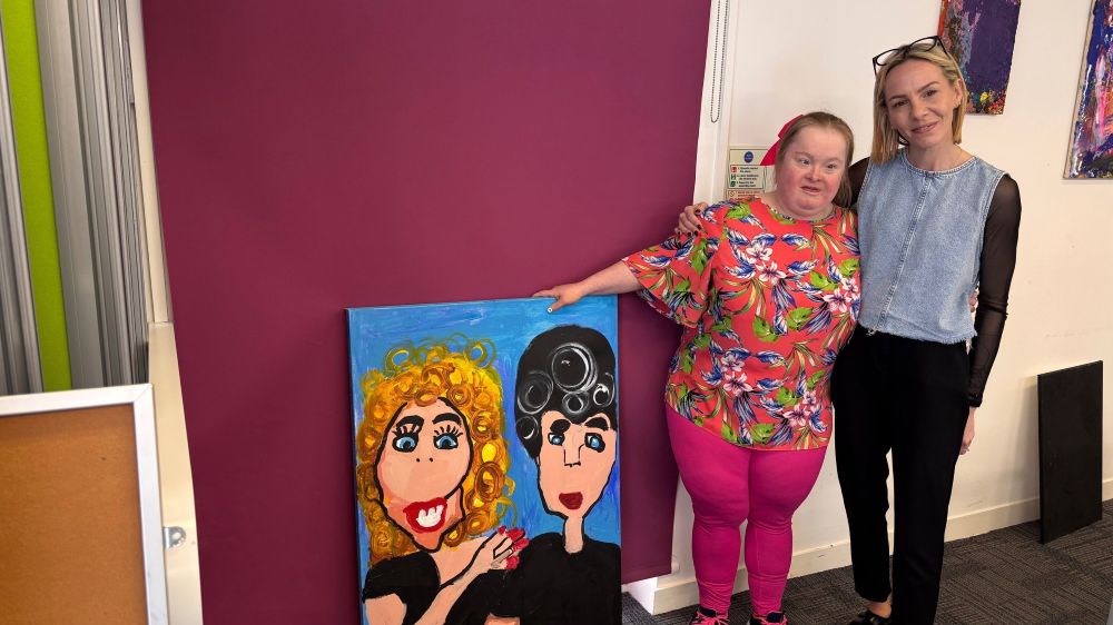 Artist Sam (left) shows her portrait of Sandy and Danny from Grease, with Toni Moden from BCIL