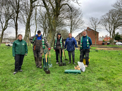Group of people on the park smiling with shovels in their hands