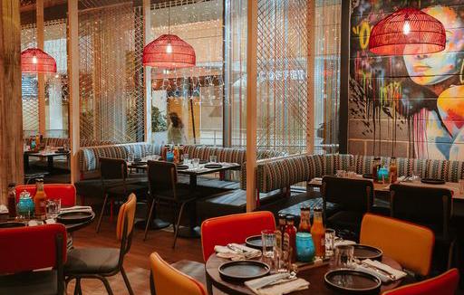 Interior design of Turtle Bay restaurant, with tables, seating and vibrant art on the walls. 