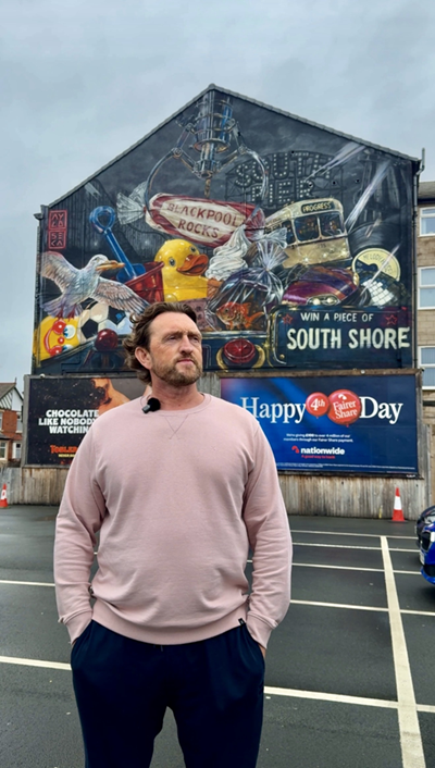 A man stands in front of a street artwork