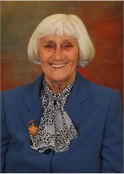 Cllr Lily Henderson, an older woman with a grey bob, is sat smiling at the camera in a blue blazer and polka dot scarf - taken in 2011