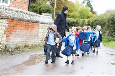 children walking in double file with a teacher looking out for them all.