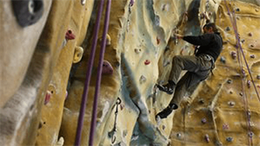 Man in a harness climbing the wall at Blackpool Sports Centre climbing wall