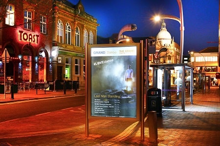 Illuminated advertising poster in town centre at night