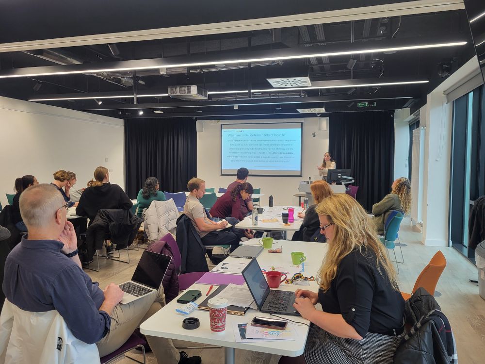 People grouped together on tables watching a presentation.