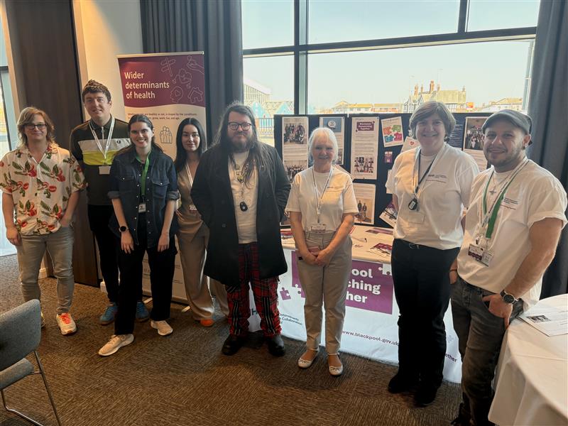 Group of co-researchers of varying ages all gathered together for a group photo in a professional event environment.