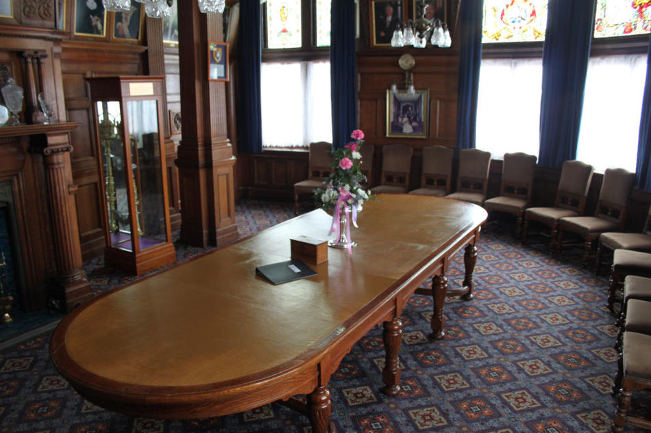 Oak paneled room with large oak table surrounded by chairs.