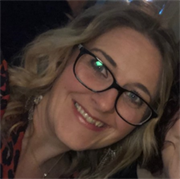 Woman with long hair and glasses smiling.