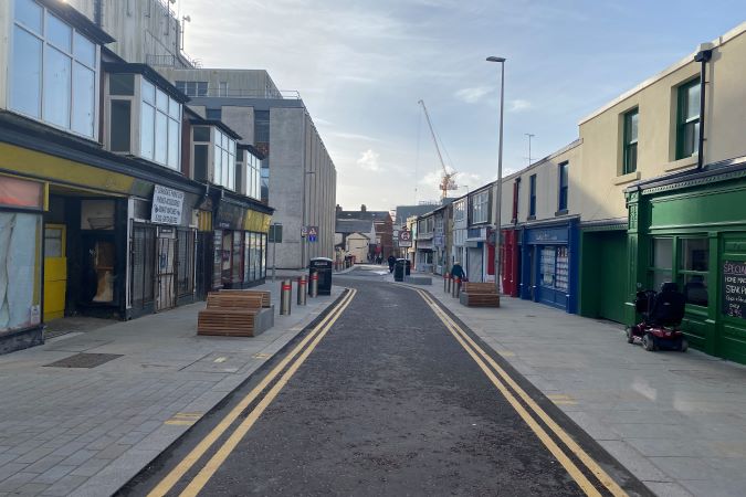 new road surface with benches and new shops on either side