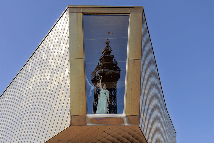 View of newly married couple in a large window looking out to tower.