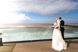 Bride and groom on balcony looking to sea.