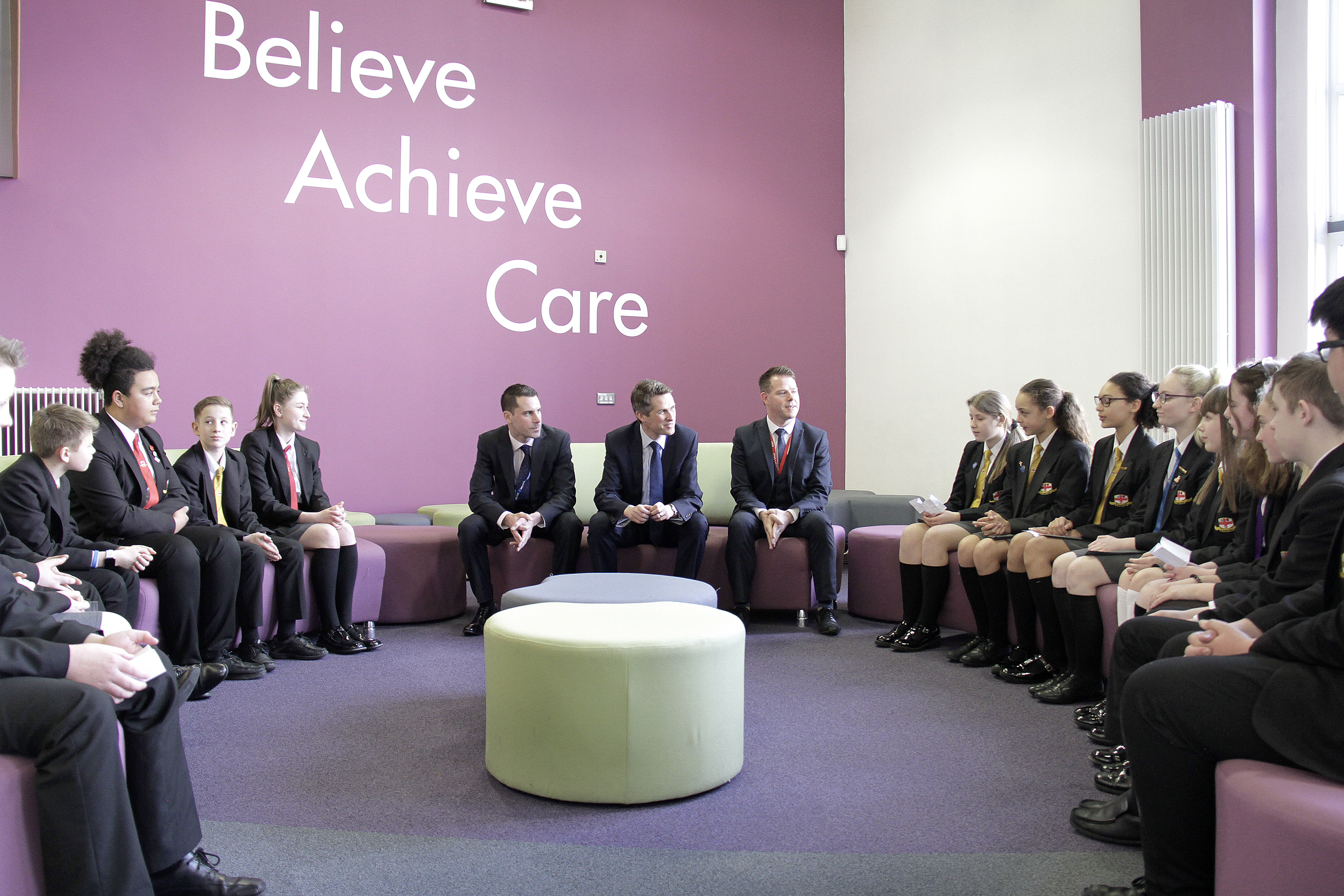 Group of adults and children sat in circle talking.