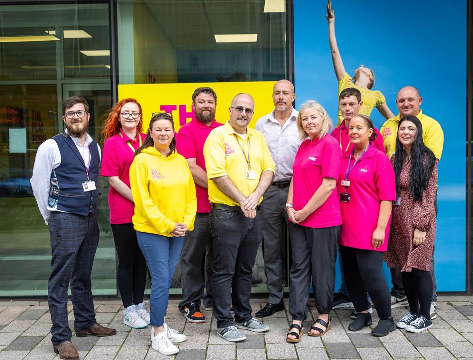 A group of people in smiling stood outside a building