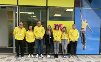 A group of seven people wearing yellow tops outside The Platform building