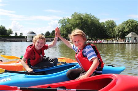 Two boys doing a high five whilst both sat in kayaks