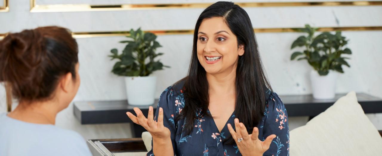 two ladies sitting across from eachother one with her hands in front of her