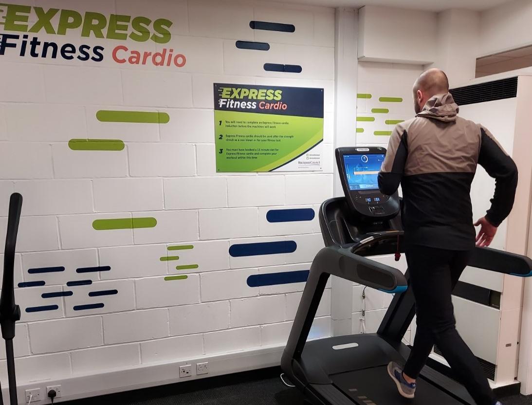 Express Fitness cardio machine with a man running on the machine