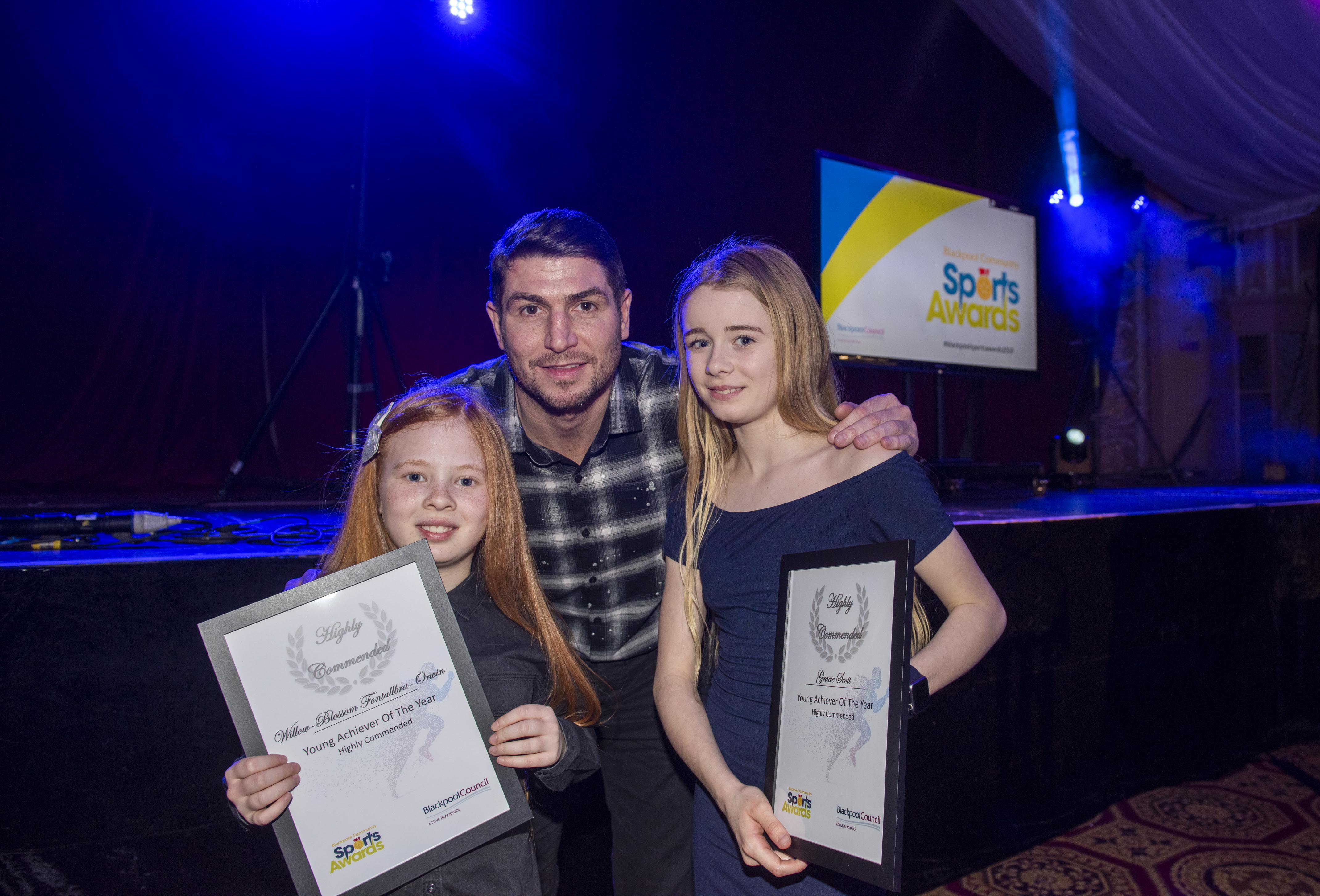 A man and two girls holding their certificates