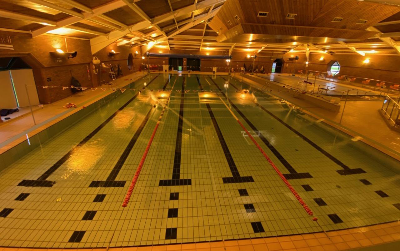 Inside Moor Parks pool hall, brick building with yellow lighting, main pool split into 3 sections for public swimming