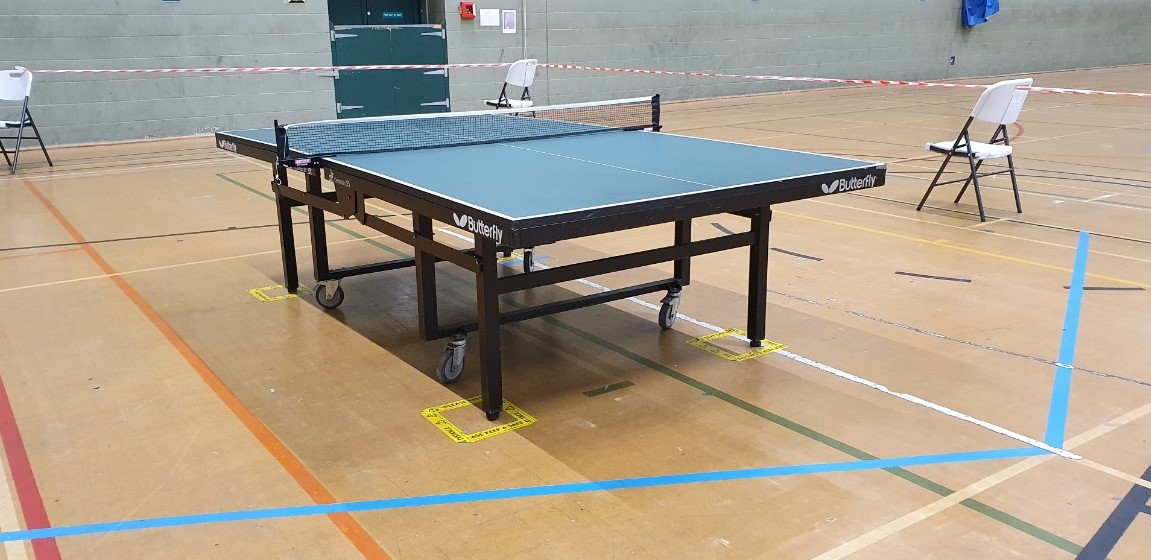 Sports Hall with a table tennis set up ready to play with tape marking the social distance area around it